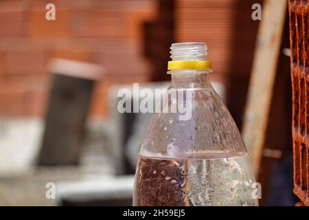 Flacher Fokus eines Stehens öffnete eine transparente Flasche Wasser auf einer braunen sonnigen Holzoberfläche Stockfoto