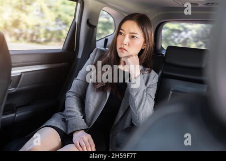 Gestresste junge Geschäftsfrau, die auf dem Rücksitz des Autos sitzt Stockfoto