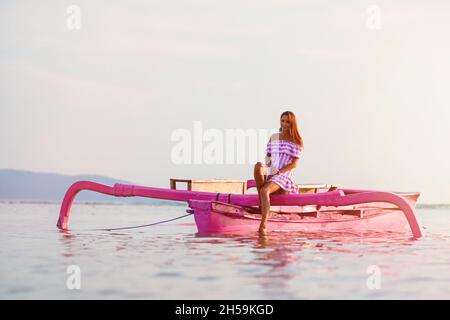 Junges Mädchen genießt eine Bootsfahrt auf dem Meer bei Sonnenuntergang. Stockfoto