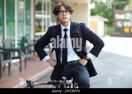 Städtischer Geschäftsmann fährt mit seinem Fahrrad zur Arbeit. Umweltfreundlicher Transport. Mann im Business-Anzug auf dem Fahrrad. Stockfoto