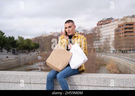 Junger Mann mit Make-up beim Sprechen lächelnd auf dem Smartphone. Stockfoto