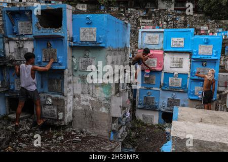 Arbeiter sanieren gestapelte Gräber, während Menschen Friedhöfe vor der Feier des All Souls’ Day auf einem öffentlichen Friedhof in Quezon City, Metro Manila, Philippinen, besuchen. Stockfoto