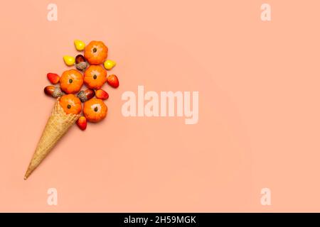 Eicheln, Zapfen, Kürbisse, Beeren in Waffelkegel für Eis auf orangefarbenem Hintergrund Draufsicht Herbstliche Flachlage Holiday Card. Stockfoto