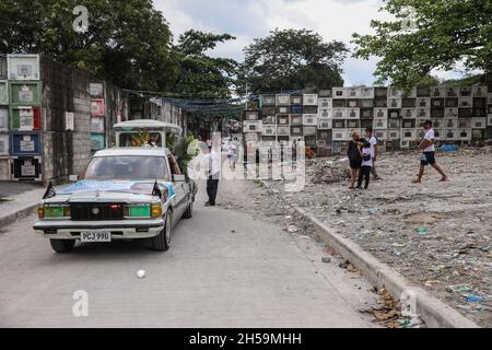 Die Menschen besuchen eine Beerdigungszeremonie, während andere ihre verstorbenen Angehörigen zur Feier des All Souls’ Day in einem öffentlichen Friedhof besuchen. Quezon City, Metro Manila, Philippinen. Stockfoto