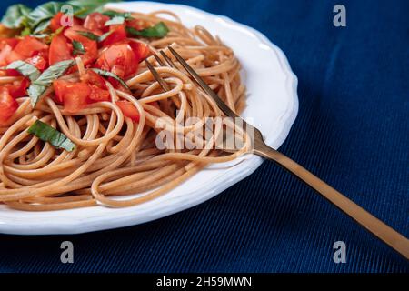 italienische vegetarische Pasta mit Tomaten und Basilikum auf einem Teller Stockfoto