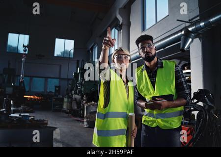 Porträt von Industrieinspektoren, die in Innenräumen in einer Metallwerkstatt eine allgemeine Überprüfung durchführen. Stockfoto