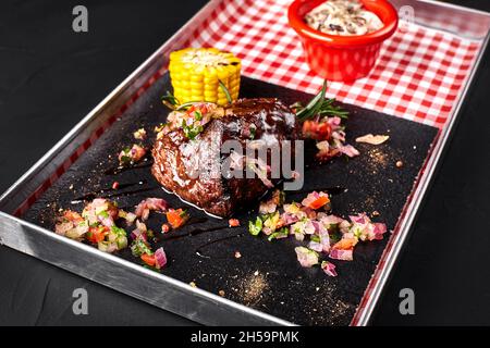 Ein Stück Steak mit Salat, Mais, Pilzsauce auf einer Tafel Stockfoto