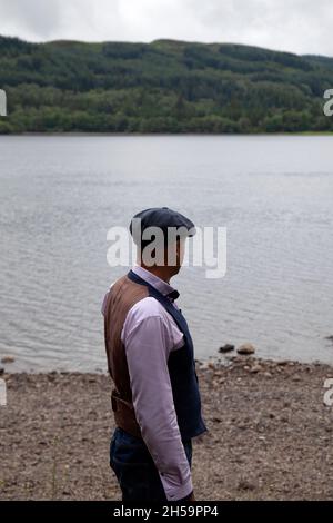 Mann in Weste und Jeans, der am See steht Stockfoto