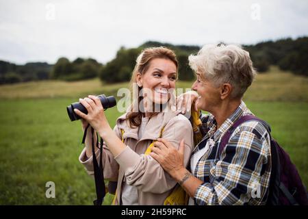 Glückliche ältere Mutter Wanderer umarmt mit erwachsenen Tochter halten Ferngläser im Freien in der Natur Stockfoto