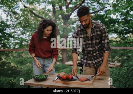 Glückliches Biracial Paar ruht sich aus und bereitet Burger im Freien in einem Baumhaus, Wochenende weg Stockfoto