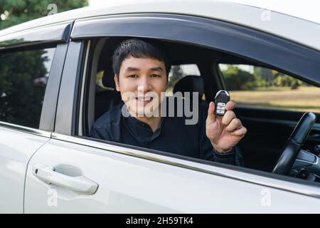 Junger Mann mit intelligenter Schlüsselfernbedienung in einem Auto Stockfoto