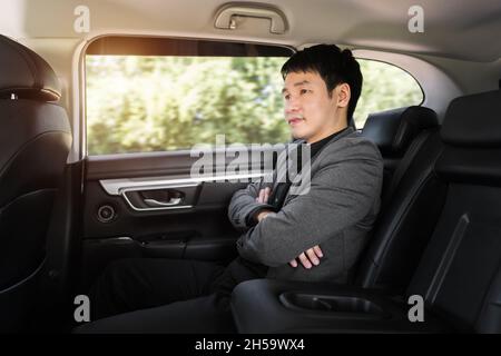 Junger Geschäftsmann, der auf dem Rücksitz des Autos sitzt Stockfoto