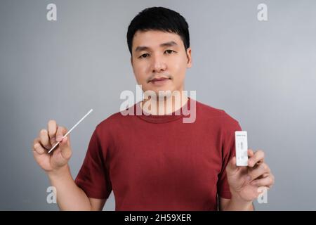 Junger Mann mit Coronavirus(Covid-19)-positivem Testergebnis mit SARS-CoV-2 Antigen-Schnelltestkits für Selbsttests zu Hause Stockfoto