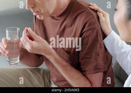 Beschnittenes Bild eines älteren Mannes, der Pillen nahm, um die Kontrolle über seinen Betreuer zu übernehmen Stockfoto