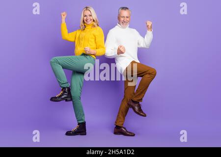 Foto von süßen glücklich reifen Frau Mann tragen gestrickte Pullover lächeln aufsteigende Fäuste isoliert lila Farbe Hintergrund. Stockfoto