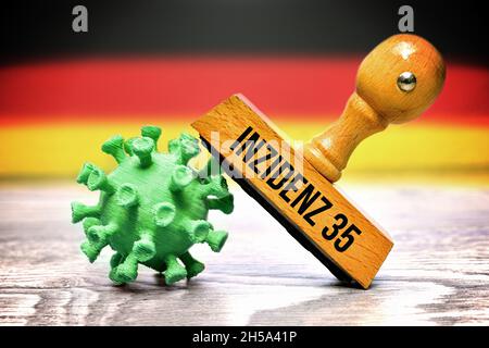 FOTOMONTAGE, Coronavirus-Modell und Stempel mit der Aufschrift Inzidenz 35 vor Deutschlandfahne Stockfoto