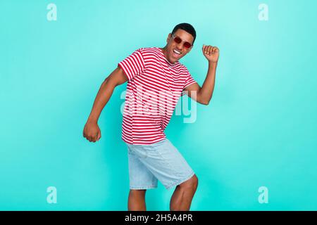 Foto von niedlichen lustigen jungen Kerl gekleidet roten T-Shirt tanzen lächelnd isoliert türkisfarbenen Hintergrund. Stockfoto