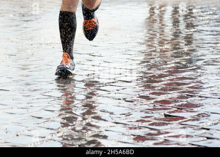 Füße einer Person, die im Regen draußen läuft Stockfoto