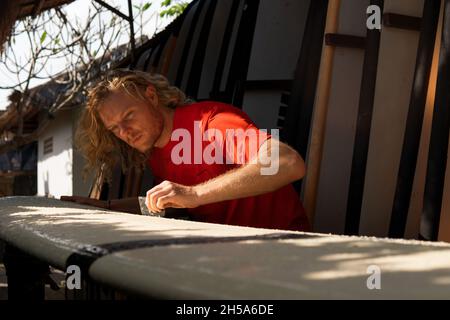 Surfer in rot kämmt das weiße Surfbrett. bali Stockfoto