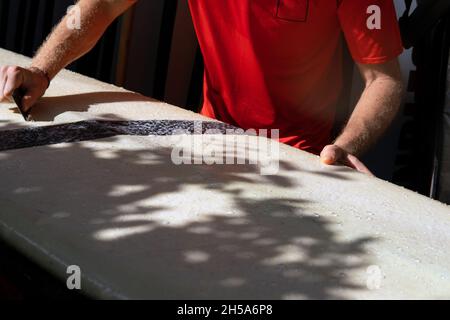 Surfer in rot kämmt das weiße Surfbrett. bali Stockfoto