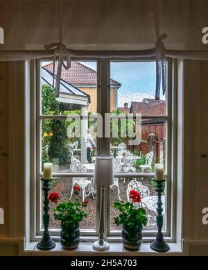 Vadstena, Schweden - 23. Mai 2021: Gemütlich eingerichtetes Fenster mit Blick auf den Hinterhof während des Regens Stockfoto