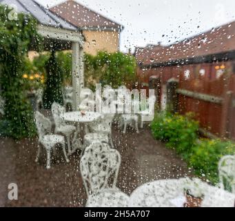 Vadstena, Schweden - 23. Mai 2021: Hinterhof des Cafés während des Regens mit Regentropfen auf der Fensterscheibe Stockfoto