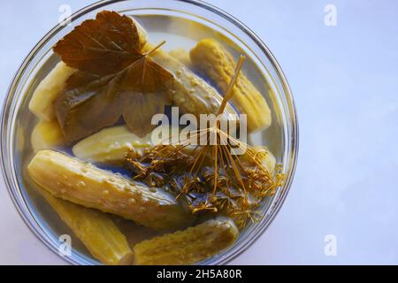 Gurken mit duftenden Gewürzen in einer runden transparenten Platte Draufsicht, Nahaufnahme Stockfoto