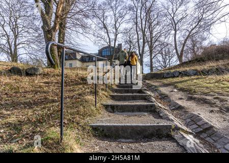 Stockholm, Schweden - 6. April 2021: Ein Paar, das nach oben in Richtung gelbes Gebäude geht Stockfoto