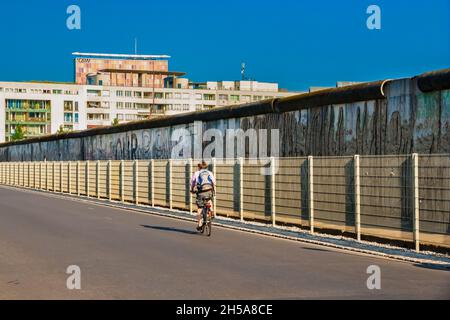 Malerische Ansicht eines Radfahrers auf der berühmten Niederkirchnerstraße und einem erhaltenen Abschnitt der Berliner Mauer im Hintergrund in Berlin,... Stockfoto