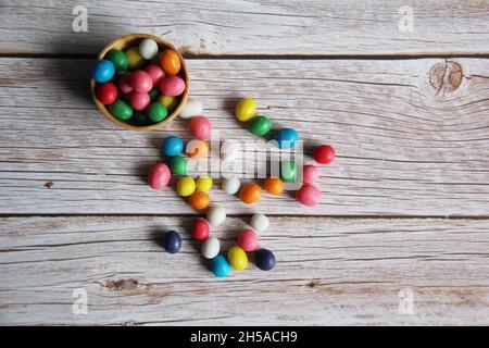 Erdnuss-Bonbons mit farbigem Zuckereier, in einer Holzschüssel auf einem alten Holztisch. Stockfoto