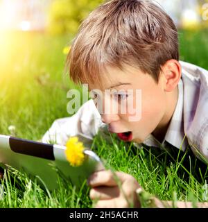 Überrascht Kind mit Tablet-Computer auf der Sommerwiese Stockfoto