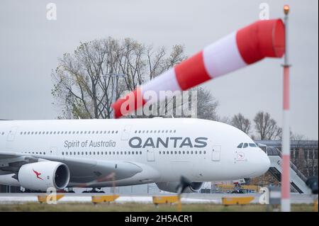 Dresden, Deutschland. November 2021. Vor dem Start am Flughafen Dresden steht ein Qantas Airways Airbus A380 hinter einer Windsack-Maschine. Nach Wartungsarbeiten an den Elbe Flugzeugwerken (EFW) wird das Flugzeug den Langstreckenflug nach Sydney antreten. Quelle: Sebastian Kahnert/dpa-Zentralbild/dpa/Alamy Live News Stockfoto