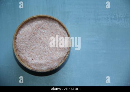 Himalaya-Salz, rosa, in einer Holzschale, mit einem hölzernen Messlöffel auf einem antiken Holztisch. Blick von oben. Stockfoto