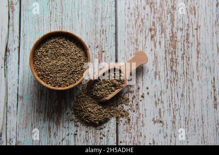 Samen von ganz Fenchel, Fenchel, Fenchel, Florentiner Fenchel, Flunder oder Kopffenchel (Foeniculum vulgare Mill) in einer Schüssel und einem Holzlöffel. Auf einem alten Tisch. Stockfoto