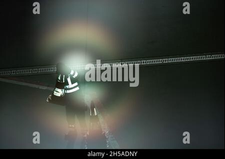 08. November 2021, Hessen, Frankfurt/Main: Die reflektierenden Streifen auf der Arbeitskleidung eines Rampenarbeiters am Frankfurter Flughafen leuchten auf, weil sie von der Sonne beleuchtet werden, die von einer Fensterscheibe reflektiert wird. Foto: Sebastian Gollnow/dpa Stockfoto