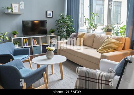 Bild eines leeren modernen Wohnzimmers mit Sofa, Sesseln und großem Fernseher Stockfoto