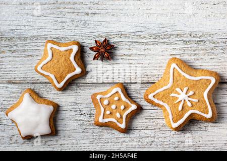 Rand von weihnachtlichen Lebkuchen in Sternform mit Glasur- und Gewürzmustern auf weißem Holzhintergrund. Draufsicht mit Kopierbereich Stockfoto