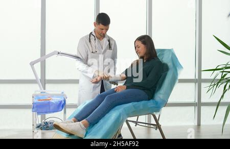 Geplante präventive medizinische Untersuchung einer jungen Frau in der Klinik. Der Arzt misst den Blutdruck des Patienten im Büro Stockfoto