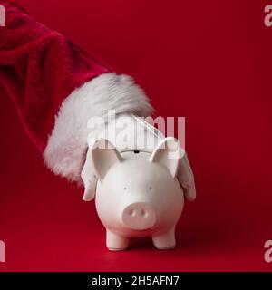 Der Weihnachtsmann hält eine Sparschwein-Spardose. Festliches Sparkonzept Stockfoto