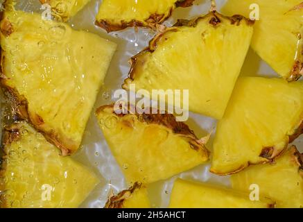 Nahaufnahme von frischen Scheiben gelber Ananas auf weißem Hintergrund. Ananasscheiben in glitzerndem Wasser auf weißem Hintergrund, Nahaufnahme. Horizontales Bild Stockfoto