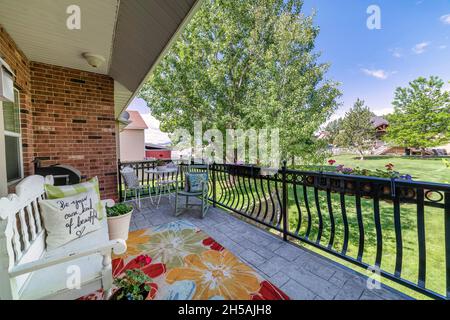 Terrasse im Freien auf einer Terrasse mit Blick auf ein großes grünes Feld mit Bäumen und Nachbarschaft Stockfoto
