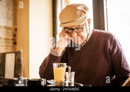 Ein älterer Mann sitzt im Café und trinkt Tee. Er ist nachdenklich. Stockfoto