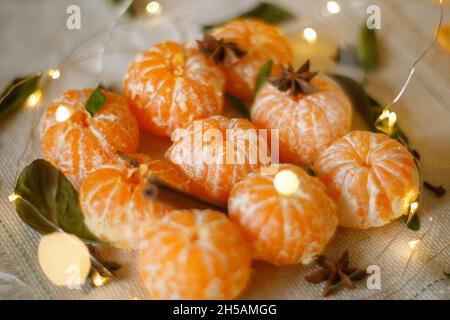 Frische Clementinen oder Mandarinen im Warenkorb auf Braune Holztisch mit Weihnachtsbeleuchtung und Zweige Stockfoto