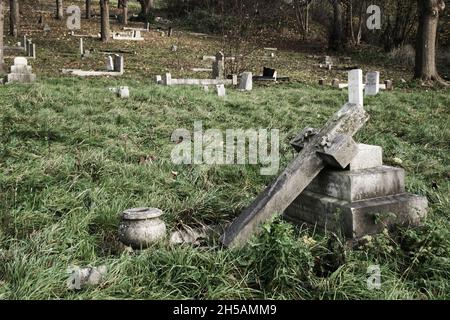 Verlassene bewachsene Friedhöfe mit grauen Steingrabsteinen Stockfoto