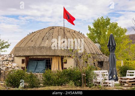 Großer militärischer Betonbunker im Kalten Krieg in Albanien mit der roten Flagge Albaniens mit dem doppelköpfigen Adler Stockfoto