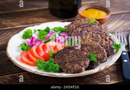 Hühnerleber-Pfannkuchen mit Gemüse auf Holzgrund. Gebratenes Huhn Leber fritters Idee. Rustikaler Stil. Stockfoto