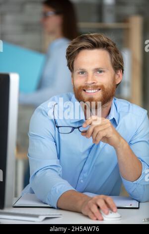 Ein gutaussehender Manager, der vor dem Laptop am Schreibtisch sitzt Stockfoto