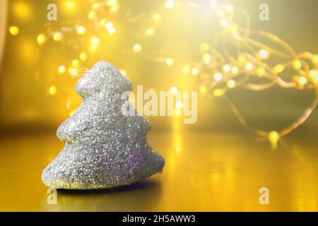 Weihnachtsspielzeug leuchtender Baum auf goldenem Hintergrund mit Lichtern. Stockfoto