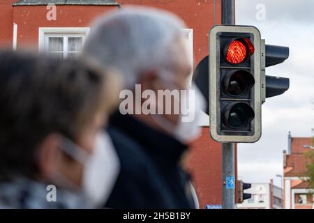 08. November 2021, Bayern, Pfarrkirchen: Eine Frau und ein Mann stehen mit einer Maske vor einer roten Ampel. Für den Landkreis Rottal-Inn gab das RKI am Montag eine Inzidenz von 833.3 an – den zweithöchsten bundesweiten Wert, dicht gefolgt vom Landkreis Mühldorf am Inn mit 831. Foto: Armin Weigel/dpa Stockfoto