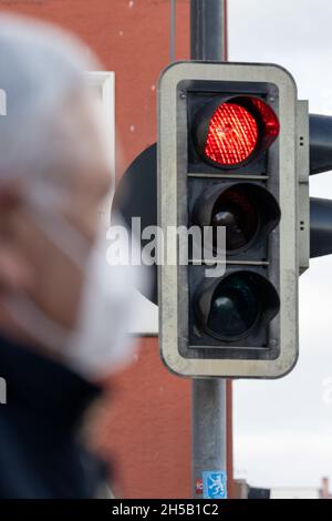 08. November 2021, Bayern, Pfarrkirchen: Ein Mann mit Maske steht vor einer roten Ampel. Für den Landkreis Rottal-Inn gab das RKI am Montag eine Inzidenz von 833.3 an – den zweithöchsten bundesweiten Wert, dicht gefolgt vom Landkreis Mühldorf am Inn mit 831. Foto: Armin Weigel/dpa Stockfoto